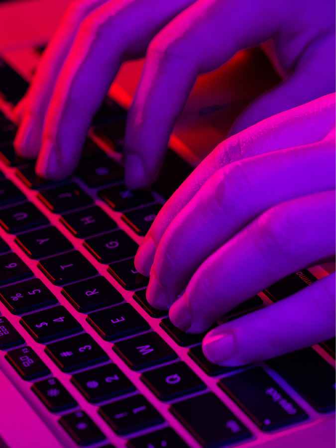 A man typing in a neon light